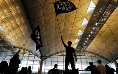 Anti-extradition bill protesters wave flags with Chinese calligraphy that reads "Liberate Hong Kong, the revolution of our times", at a mass demonstration after a woman was shot in the eye during a protest at Hong Kong International Airport, in Hong Kong