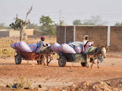 Displaced women, who fled from attacks of armed militants in town of Roffenega, ride donkey carts loaded with food aid at the city of Pissila