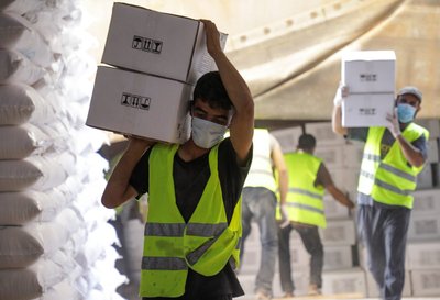 Workers carry boxes of humanitarian aid near Bab al-Hawa crossing at the Syrian-Turkish border, in Idlib governorate