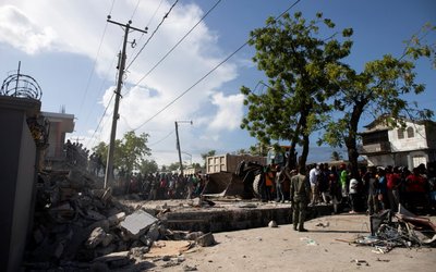 People look at a damaged house after a 7.2 magnitude earthquake in Les Cayes