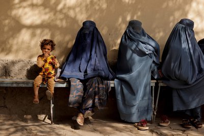 A girl sits with women wearing burqas outside a hospital in Kabul