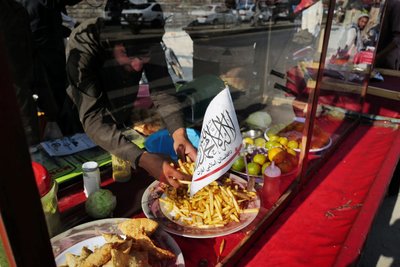 A Taliban flag of the Islamic Emirate of Afghanistan is attached on a food street cart at a market in Kabul