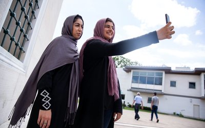 Two Muslim women take pictures after the first Friday prayers during the month of Ramadan at Diyanet Center of America in Lanham