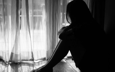 black and white of sad woman hug her knee and cry. Sad woman sitting alone in a empty room beside window or door