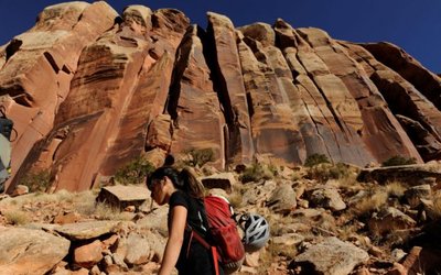 A rock climber walks below a rock facing near the Indian Creek area of Bears Ears, New Mexico
