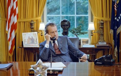 President Richard Nixon seated at his desk in the White House Oval Office