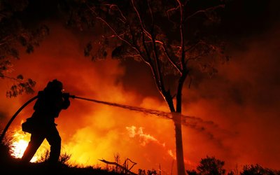 A firefighter working on extinguishing the Lilac Fire a fast moving wildfire is seen in Bonsall
