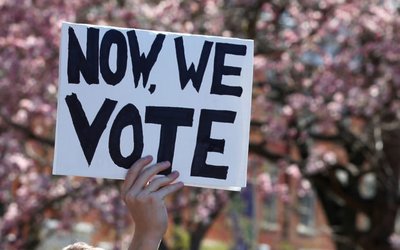 A youth holds up a "Now We Vote" sign as they take part in a National School Walkout anti-gun march in Washington Square Park in the Manhattan borough of New York City