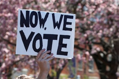 A youth holds up a "Now We Vote" sign as they take part in a National School Walkout anti-gun march in Washington Square Park in the Manhattan borough of New York City