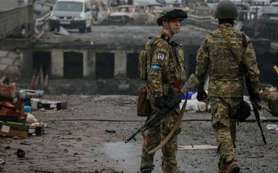 Ukrainian servicemen stand by a destroyed bridge as Russia's invasion of Ukraine continues, in the town of Irpin outside Kyiv