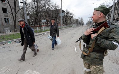 Service members of pro-Russian troops stand guard in a street in Mariupol