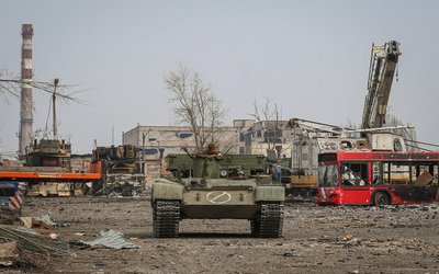 Service members of pro-Russian troops look on as they ride an armoured vehicle during fighting in Ukraine-Russia conflict in the city of Mariupol