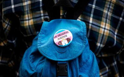 A "We Deserve Justice" button is seen as people protest the recent killings of three trans women, Muhlaysia Booker, Claire Legato, and Michelle Washington during a rally at Washington Square Park in New York