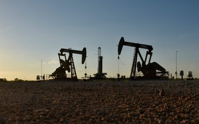 FILE PHOTO: Pump jacks operate in front of a drilling rig in an oil field in Midland