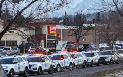 Law enforcement vehicles line up at the perimeter of a shooting site at a King Soopers grocery store in Boulder
