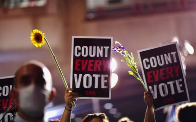 Activists hold up flowers and signs stating "COUNT EVERY VOTE" across the street from where votes are still being counted, two days after the 2020 U.S. presidential election, in Philadelphia