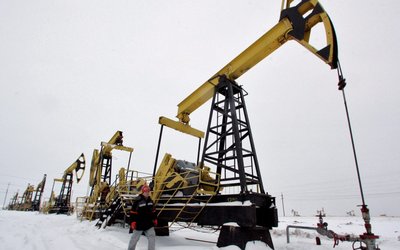 FILE PHOTO: A worker walks past pump jacks at UdmurtNeft's Gremikhinskoye oil field east of Izhevsk