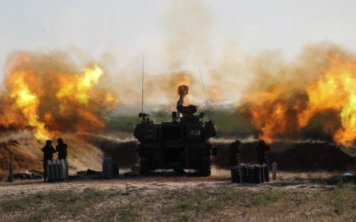 Israeli soldiers work in an artillery unit as it fires near the border between Israel and the Gaza strip, on the Israeli side