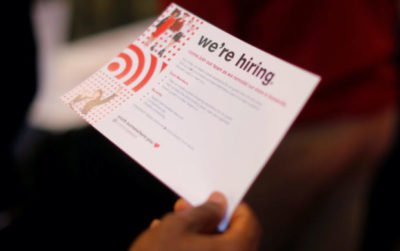 A job seeker holds a "We're Hiring" card while talking to a representative from Target at a City of Boston Neighborhood Career Fair on May Day in Boston