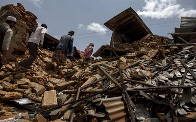 local villagers walk amid debris at a devastated area following Saturday's earthquake, at Asslang village, in Gorkha