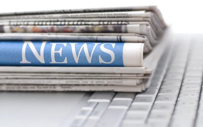 Stack of newspapers resting on laptop keyboard