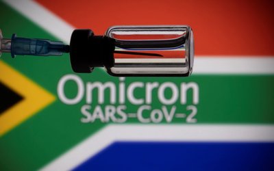 A vial and a syringe are seen in front of a displayed South Africa flag and words "Omicron SARS-CoV-2" in this illustration taken