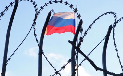The Russian flag is seen behind a razor wire fence on the roof of the Russian Consulate General in Kharkiv