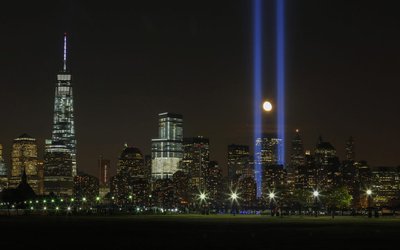 The moon rises between the "Tribute in Light" illuminated next to One World Trade Center during 911 anniversary, as seen from Jersey City, New Jersey