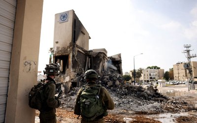 Israeli soldiers look at the remains of a police station following a mass infiltration by Hamas gunmen from the Gaza Strip, in Sderot