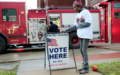 Campaign worker Kamisthial Jones adjusts a Vote Here sign outside a voting place for the midterm election in Detroit