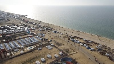 A drone view of Palestinians gathering on a beach in the hope of getting aid air-dropped over Gaza is seen, amid the ongoing the conflict between Israel and Hamas, in Deir Al-Balah in the central Gaza Strip