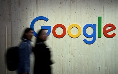 FILE PHOTO: People walk next to a Google logo during a trade fair in Hannover Messe