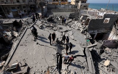 Palestinians inspect the site of an Israeli strike on a residential building, in Deir Al-Balah