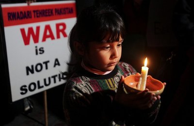 A girl holds a candle as she takes part with others in a peace vigil for the global standout for peace in South Asia, in Lahore