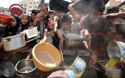 Palestinians wait to receive food from a charity kitchen, in Gaza City