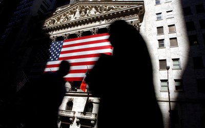 FILE PHOTO: The sun lights the exterior of the New York Stock Exchange, as people walk past on the shadowed street