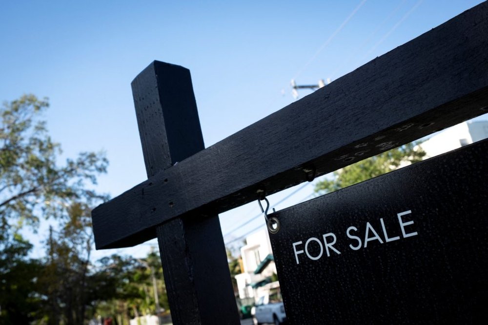 A "For Sale" sign stands at a house in Miami
