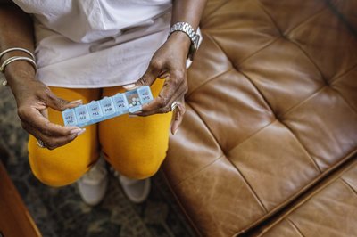 Black woman holding plastic pill box organizer