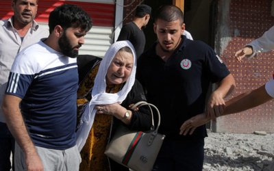 Woman is taken out of a building after it was hit by mortar shells fired from Syria, in the Turkish border town of Akcakale
