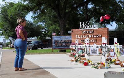 A woman brings flowers to a memorial for the victims of a school shooting at Robb Elementary School in Uvalde