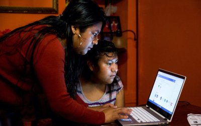 Belen Cruz helps her daughter to sign in online as schools resumed with online learning in York City