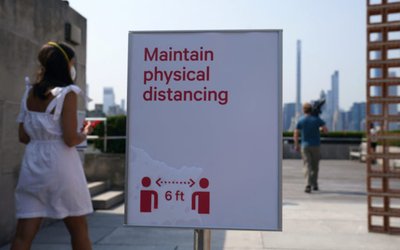 People walk past a sign asking for social distancing on the new rooftop terrace at The Metropolitan Museum of Art on their first day open since closing due to the coronavirus disease (COVID-19) outbreak