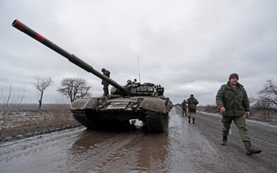 Servicemen of pro-Russian militia walk next to a military convoy in the Luhansk region