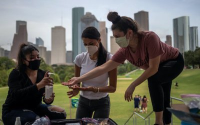 Mask wearing residents share hand sanitizer in front of skyline amid global outbreak of coronavirus disease in Houston, Texas